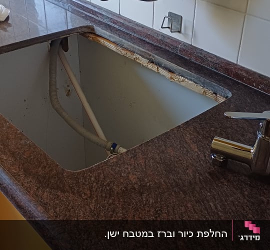 כיור מטבח עם ברז וצינור חשוף מתחת לשיש